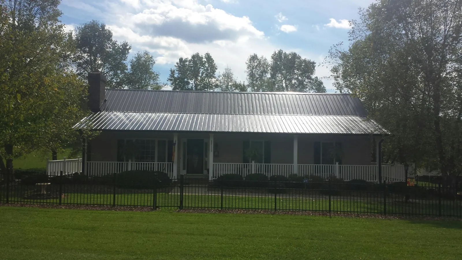 Gray metal roof on a brick ranch with a full width front porch — Gutter Guard Installation work by our crew in Joy