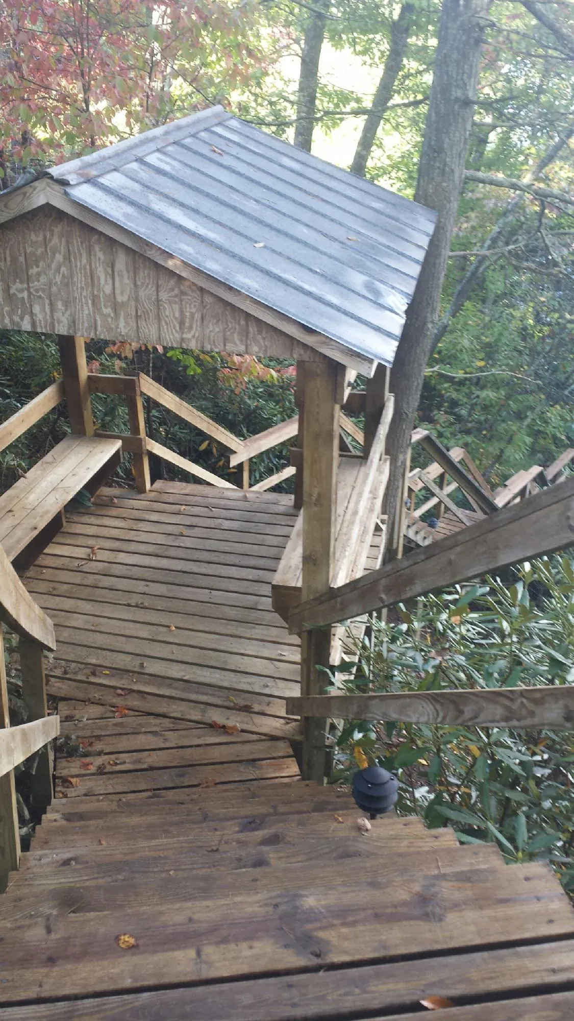 Metal roofed shelter over wooden steps on a wooded walkway — Skylight Repair & Installation work by our crew in Joy